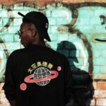 Streetwear - Man Wearing Black Long-sleeved Shirt Stands Near Red Wall