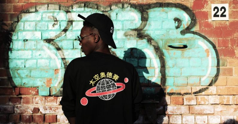 Streetwear - Man Wearing Black Long-sleeved Shirt Stands Near Red Wall