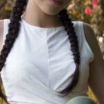 Looks - Woman in White Tank Top and Gray Pants Sitting on Green Grass Field