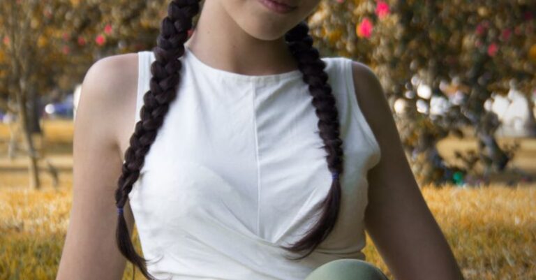 Looks - Woman in White Tank Top and Gray Pants Sitting on Green Grass Field